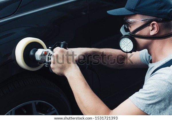 car cleaner in respirator and protective
glasses polishing car with buffer
machine