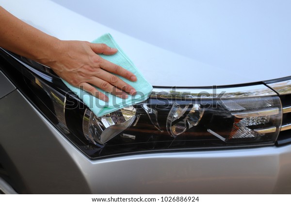 Car cleaning with green cloth by woman\'s hand in\
sunny day.
