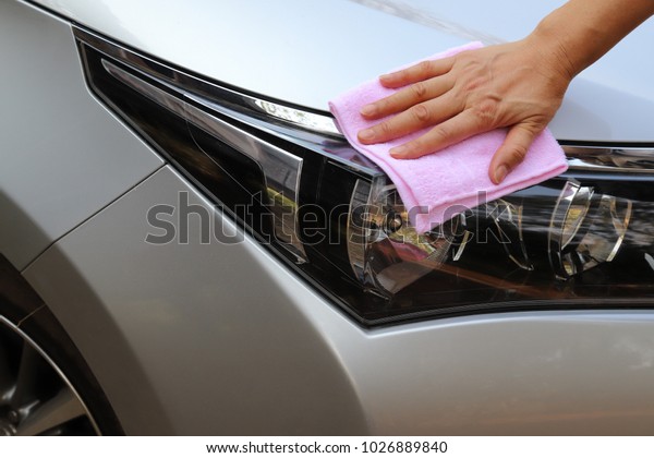 Car cleaning with pink cloth by woman\'s hand in\
sunny day.
