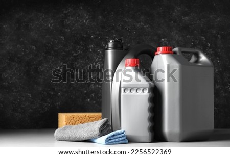 Car cleaning products, canisters with motor oil and microfiber fabric on light grey table. Space for text