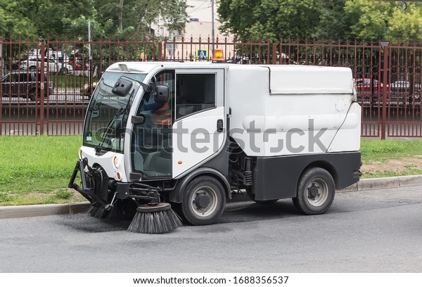 car for cleaning roads with round brushes on a\
city street.