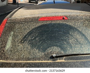 Car in Colmar, France covered with windblown Sahara sand and dust. Rear view of car with even layer of orange colored fine dust.