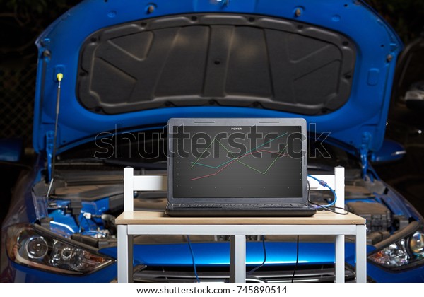 Car computer diagnostic concept. Table with\
laptop show car perfomance