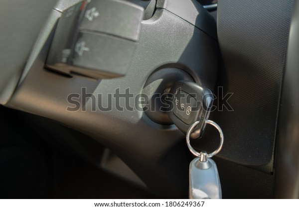 A car control panel in\
dark colors with inserted ignition key in sunny summer day, close\
up view