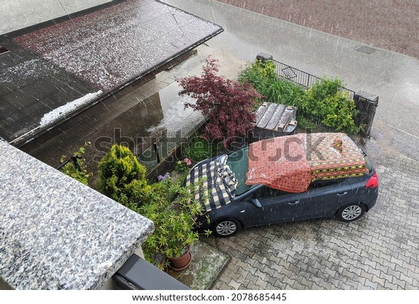 Car covered in\
blankets during strong hail storm. Car protection against hail\
during stormy weather