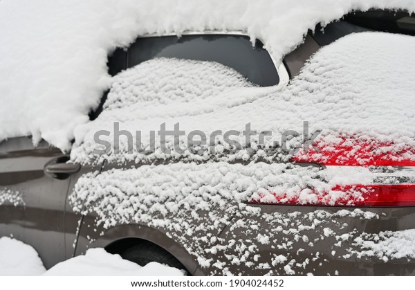 Car covered by snow after a snow blizzard, back\
side view.