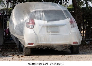 Car covered with large plastic bag for prevention. Protection of parking car with transparent coverage. - Shutterstock ID 2252880115