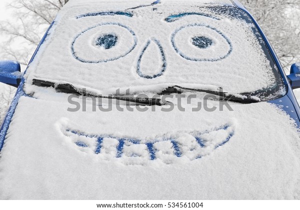 Car covered\
snow with drawn smiley face in windshield against the backdrop of\
snowy trees, beautiful winter\
day