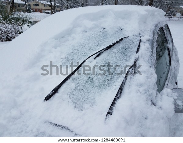 car covered with snow and ice in the winter and\
windshield wipers