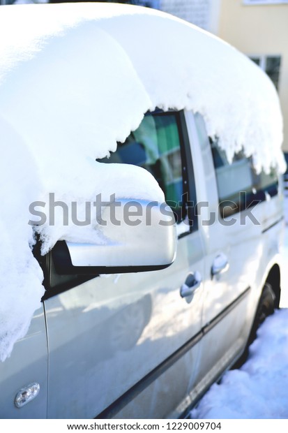 car covered\
with snow, a mirror and a window in the snow, reflections in the\
glass, a frosty sunny day,\
close-up