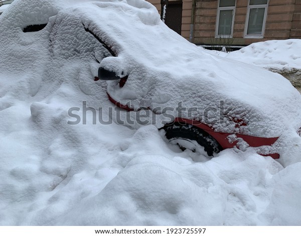 The car was covered with snow in the parking lot.
Cars under a large layer of snow. Snowfall on the streets of a
European city.