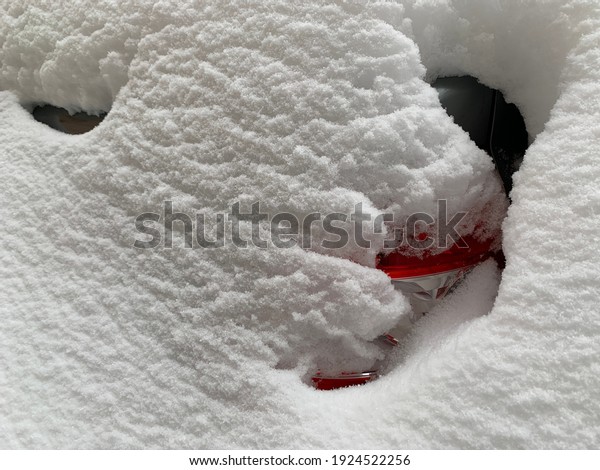 The car was covered with snow in the parking lot.\
Cars under a large layer of snow. Snowfall on the streets of a\
European city.