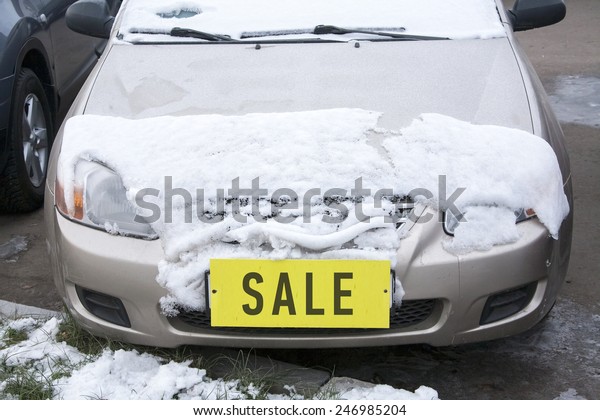 car covered with snow with a yellow label \'sale\'\
instead of the number