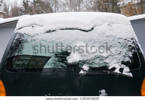  The car, covered with thick layer of snow.\
Negative consequence of heavy snowfalls. Close-up shot of a car\'s\
windscreen wiper covered in\
snow