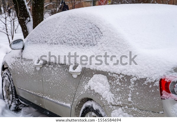 The car, covered with thick layer of snow.\
Negative consequence of heavy snowfalls. Side hundred cars with\
different patterns.