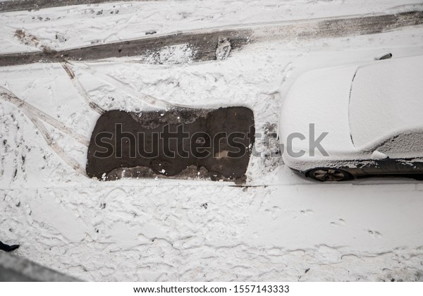 The car, covered with thick layer\
of snow. Negative consequence of heavy snowfalls. parked cars\
covered with snow during snowing in winter time. Top\
view.
