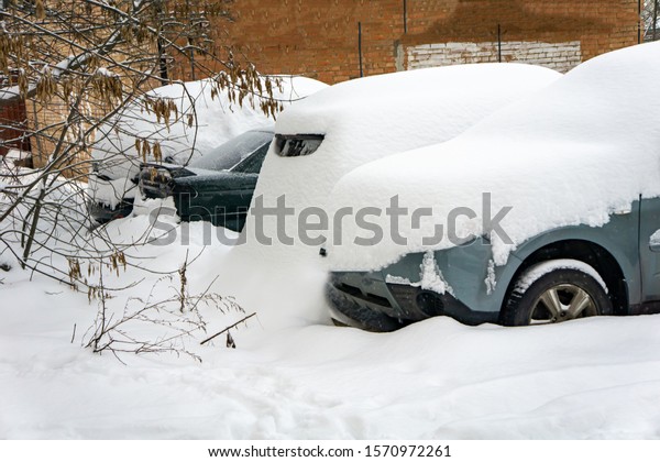 The car, covered with thick layer of snow.\
Negative consequence of heavy snowfalls. parked cars covered with\
snow during snowing in winter\
time