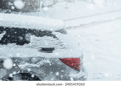 Car covered with a thin layer of snow. Vehicle after snowstorm parked on the street side. Rear side of the car with snow. Estate wagon. Touring wagon in winter.
