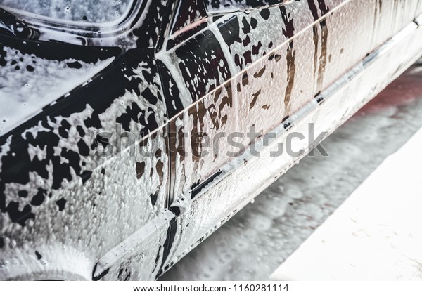 Car covered in white foam during cleaning,\
carwash washing process, car in\
soup.