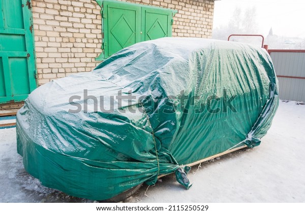 Car covered in winter. Sheltered car\
in winter. Tent for the car. Car storage in\
winter.