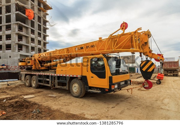 Car crane on residential building construction\
site. Moscow 2019. Mobile crane is cable-controlled crane mounted\
on crawlers or rubber-tired carriers or hydraulic-powered crane\
with telescoping boom.