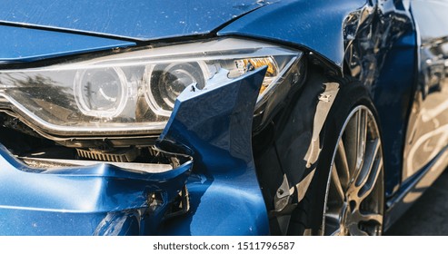 Car crash or accident. Front fender from a blue car and light damage and scratchs on bumper. Broken vehicle detail or close up. 