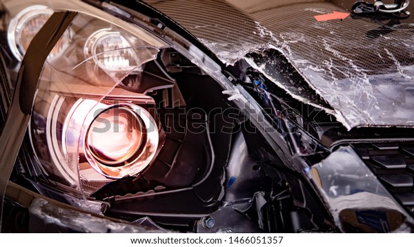 Car crash accident on the road. Damaged headlight\
and front bumper of black motor vehicle after collision. Auto\
insurance concept