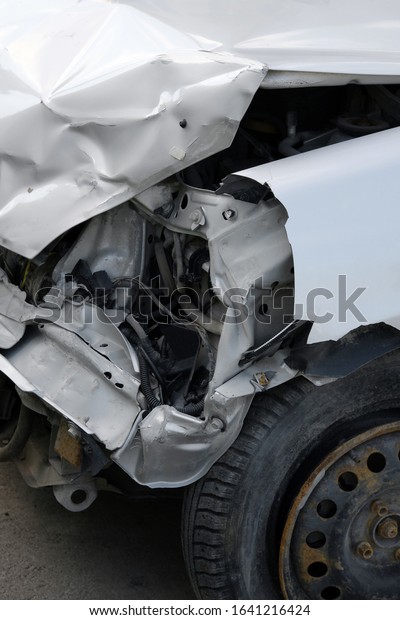 Car crash or accident.Front side of a\
damaged car. A white car heavily damaged on the front side. Broken\
vehicle detail or close up. Car insurance concept.\
