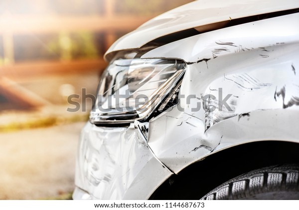 Car crash of front bumper\
white car. Vehicle accident on road with broken light and damage\
fender.