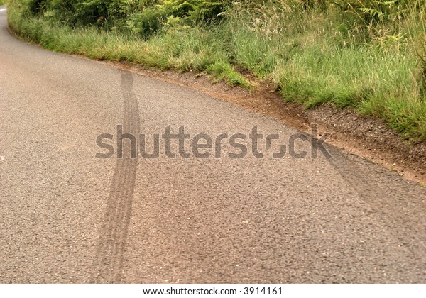 car crash skid marks on a rural road heading\
into the undergrowth