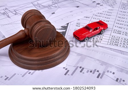 Car credit debt concept. Wooden judgle gavel and miniature toy red car on a pile of papers.