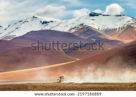 Car crossing dirt road in Atacama desert, volcanic arid landscape in Chile