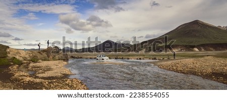 Car crossing shallow river landscape photo. Beautiful nature scenery photography with old mountains on background. Idyllic scene. High quality picture for wallpaper, travel blog, magazine, article
