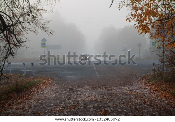 car at the\
crossroads in autumn and foggy\
time
