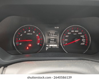 car dashboard, focusing on the illuminated instrument cluster. tachometer on the left, speedometer on the right, and a central digital display showing time, fuel efficiency, travel range, and odometer