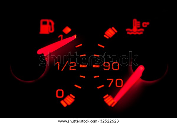 Car dashboard gauges illuminated over a black\
background. Shallow depth of\
field