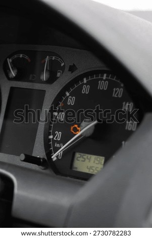 Car dashboard with illuminated engine light, speedometer needle near zero, odometer reading , amber indicator