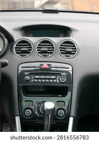 Car dashboard interior with central console and air conditioning vents. Automotive technology and driving control panel including audio system, gear stick, and climate control interface.