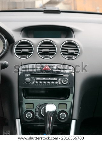 Car dashboard interior with central console and air conditioning vents. Automotive technology and driving control panel including audio system, gear stick, and climate control interface.