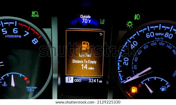 Car dashboard with low fuel warning displayed on\
the monitor. High fuel prices concept with a modern car dash,\
vibrant colors.
