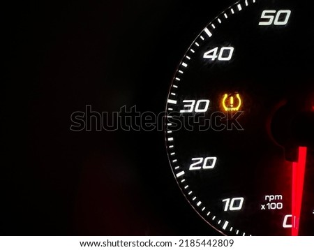 Car dashboard panel icon on a black background. Tire pressure monitoring.