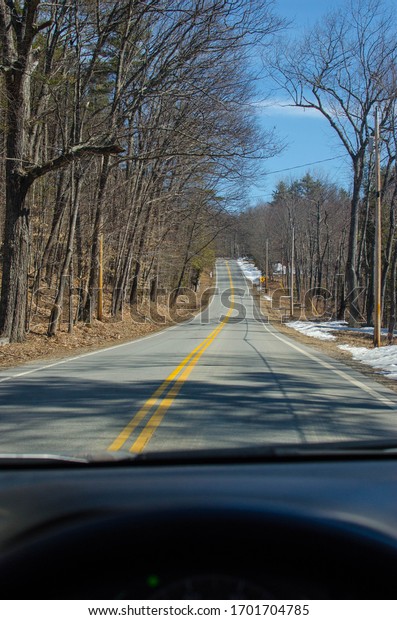 Car dashboard with road in\
woods