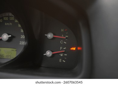 A car dashboard showcasing its speedometer, fuel gauge, and temperature gauge. The digital display indicates mileage, and an illuminated warning light highlights a potential issue with the vehicle.