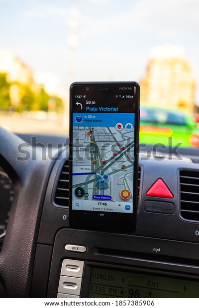 In car\
dashboard view with smartphone showing Police on Waze maps. Driver\
using Waze maps in Bucharest, Romania,\
2020