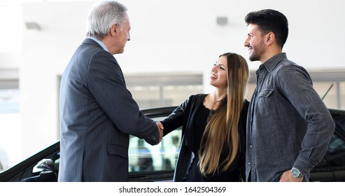 Car Dealer Giving A Handshake To A Young Couple