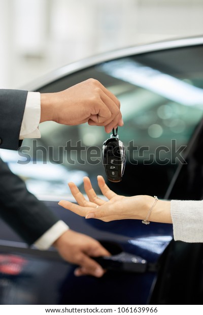 Car dealer giving\
keys to female customer