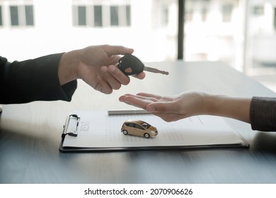 The car dealer provides advice on loans, insurance details, and car rental information, and delivers the car with the keys after the rental contract is signed. - Shutterstock ID 2070906626