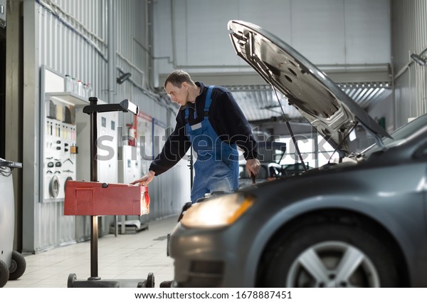 Car dealer service, auto mechanic\
checking of the headlights with a headlight tester\
device