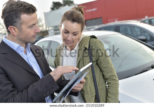 Car\
dealer showing car specifications to client on\
tablet