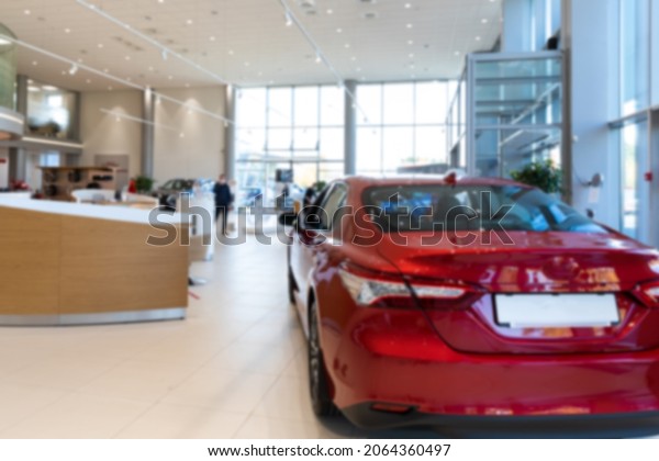 car dealer showroom interior with red car in the\
foreground, focus on car